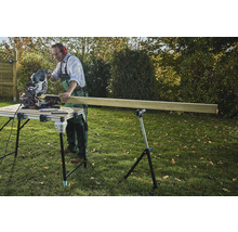 Hantverkare sågar trä med en kap- och gersåg på ett sågbord i trädgården.