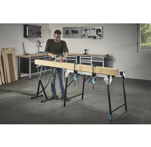 Man fräser trä på en arbetsbänk med skruvtvingar i en verkstad