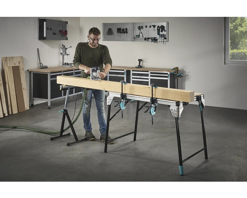 Man fräser trä på en arbetsbänk med skruvtvingar i en verkstad