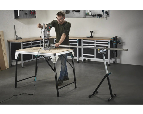 Man arbetar med en borrmaskin på ett arbetsbord, med verktyg och en arbetsbänk i bakgrunden.