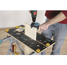 En person borrar en träplanka med en borrmaskin på en arbetsbänk.