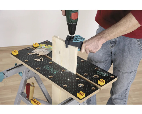 En person borrar en träplanka med en borrmaskin på en arbetsbänk.