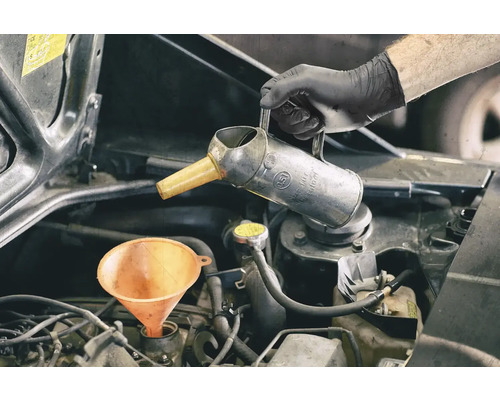 Motorolja fylls på med tratt och oljekanna
