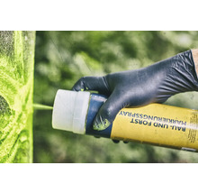 En person med handskar använder markeringsspray för konstruktion och skog.