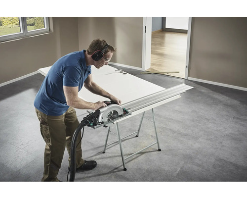 Hantverkare som sågar en dörr med en cirkelsåg på en arbetsbänk.