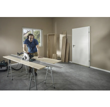 Man skär trä med en cirkelsåg på en arbetsbänk i ett rum.