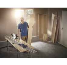 Man med cirkelsåg och styrskena som skär trä för en hylla