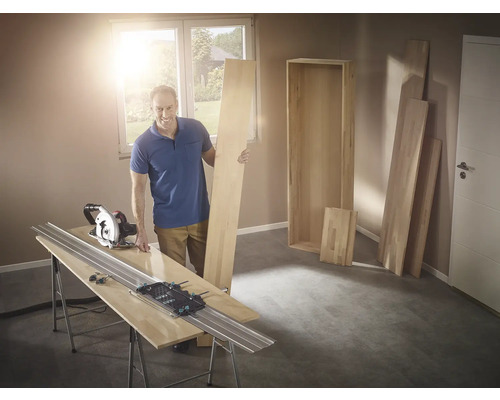 Man med cirkelsåg och styrskena som skär trä för en hylla