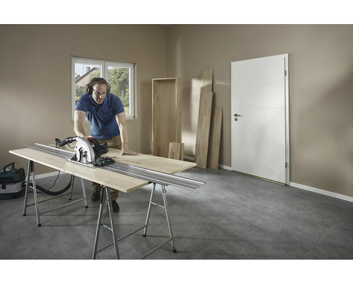 Man skär trä med en cirkelsåg på en arbetsbänk i ett rum.