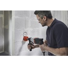 En man borrar ett hål i en vägg med en hålsåg.