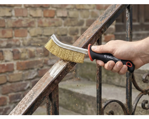 En hand använder en stålborste för metallrengöring på ett räcke. Rautner logotyp synlig.