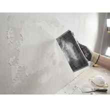 Hantverkare slipar vägg med slipverktyg. Gör-det-själv-projekt för väggrenovering.