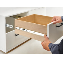 Öppet lådutdrag på ett vitt skåp med lådskena