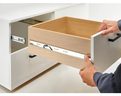 Öppet lådutdrag på ett vitt skåp med lådskena