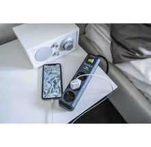 Grenuttag med överspänningsskydd och ansluten telefon på ett nattduksbord