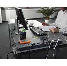 Arbetsplats med grenuttag, elektroniska enheter och person