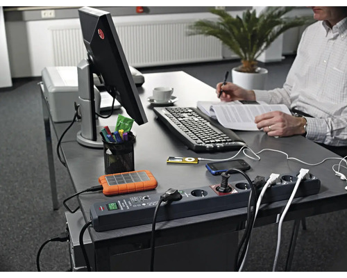 Arbetsplats med grenuttag, elektroniska enheter och person