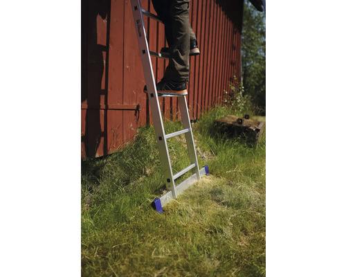 Person på en aluminiumstege framför en röd trävägg i trädgården