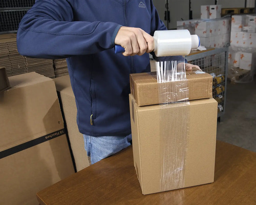 Man packar kartonger med sträckfilm