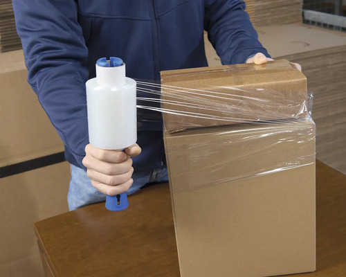 En person packar kartonger med sträckfilmsförpackning.