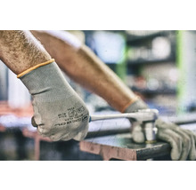 En person bär skyddshandskar och använder en skiftnyckel.