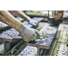 En person mäter en metallbit med ett digitalt skjutmått på en balk.