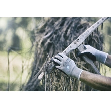 Person med handskar som plockar upp torrt gräs med en träkratta