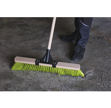 Kvast med träskaft och färgade borst i bruk