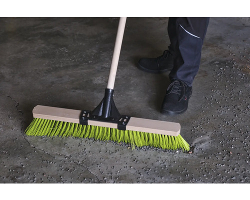 Kvast med träskaft och färgade borst i bruk