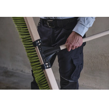 Person håller en grön sopborste med träskaft.