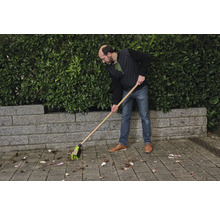 En person sopar löv med en gatukvast.