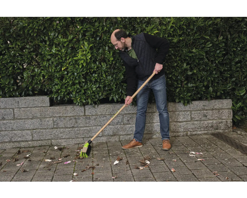 En person sopar löv med en gatukvast.