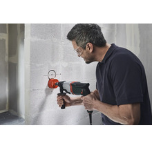 En man borrar ett hål i en betongvägg med en kärnborrmaskin.