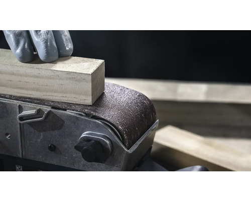 Närbild av en bandslip som jämnar ut en träbit