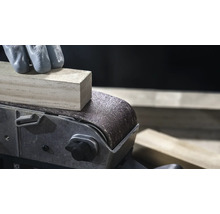 Närbild av en bandslip som jämnar ut en träbit