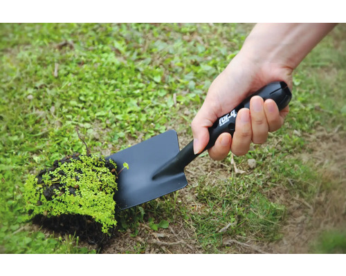 En person håller en svart trädgårdsspade med en bit jord och växter.