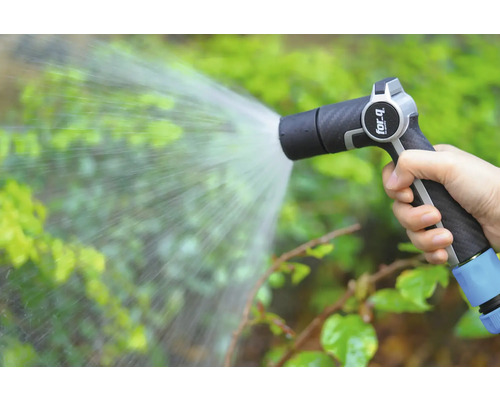 En hand håller en trädgårdsspruta som sprutar vatten på växter