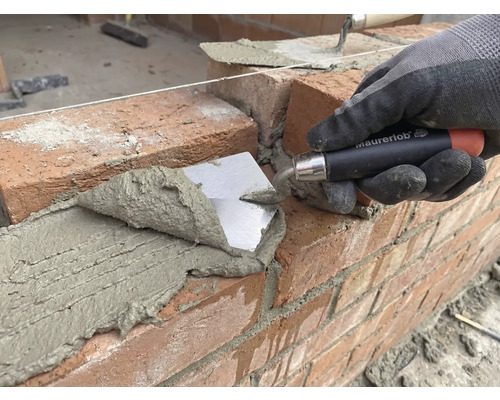 Murare lägger tegelsten med en murslev på en byggarbetsplats