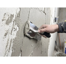 Hantverkare applicerar puts på en vägg med en spackel.