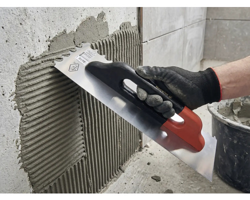 Applicera kakelfix på en vägg med en spatel i rostfritt stål