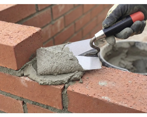 Murare använder en murslev och murbruk för att bearbeta tegelstenar.