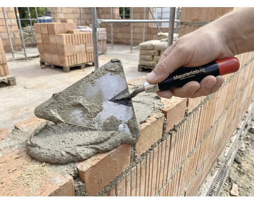 Murare lägger tegelstenar med en murslev och murbruk.