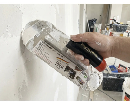 Glättkelle Superglatt med handtag i handen vid putsning av en vägg