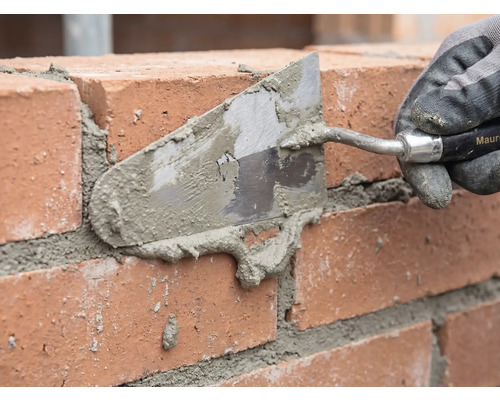 Murare som fogar en tegelvägg med en murslev