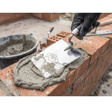 Murare som arbetar med murslev, murbruk och tegelstenar