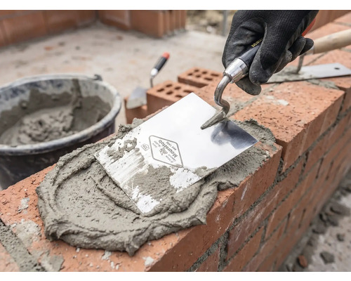 Murare som arbetar med murslev, murbruk och tegelstenar