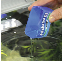 JBL Biotopol vattenberedningsmedel hälls i ett akvarium med ett doseringsmått.