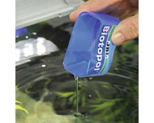 JBL Biotopol vattenberedningsmedel hälls i ett akvarium med ett doseringsmått.