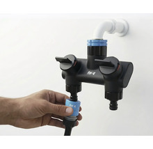 Fotografi av ett for_q dubbelbatteri med vattenanslutning och hand som fäster en slang.