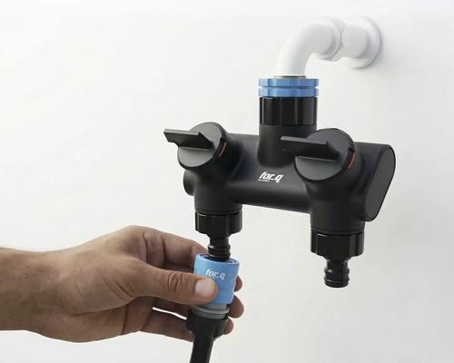 Fotografi av ett for_q dubbelbatteri med vattenanslutning och hand som fäster en slang.